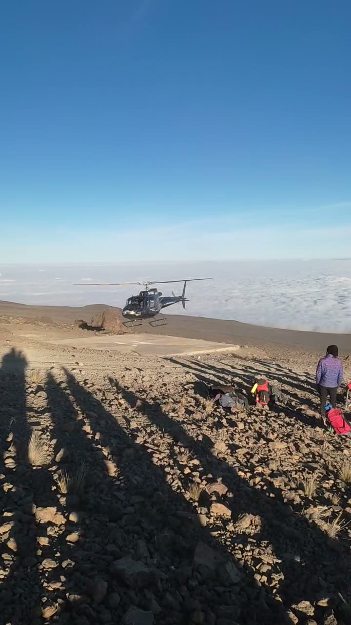 A rescue helicopter landing on a high-altitude helipad on Mount Kilimanjaro above the cloud line